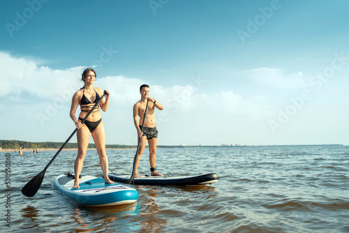 People man and woman ride water sport sup board. Sea view horizon
