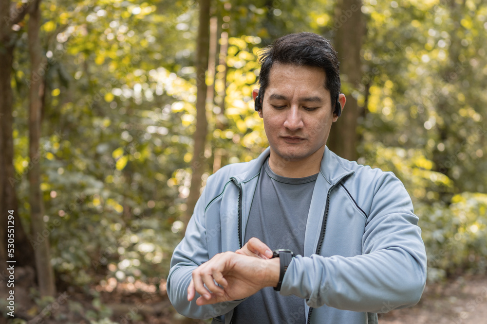 Close up man using smart watch to monitor performance, setting up his smart watch before exercise on path forest. Close up man using smart watch to monitor performance, setting up his smart watch before exercise on path forest.