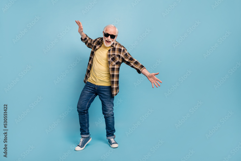 Photo of excited cute man pensioner dressed checkered shirt eyewear dancing isolated blue color background Photo of excited cute man pensioner dressed checkered shirt eyewear dancing isolated blue color background