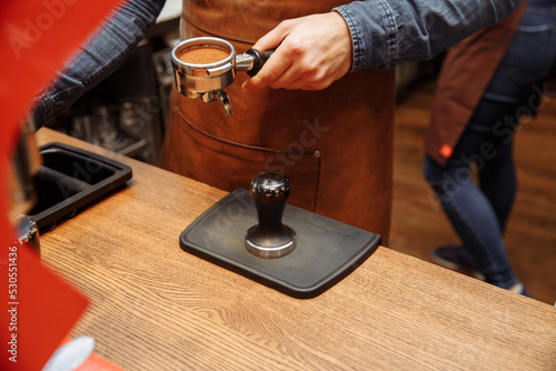 Preparation of coffee in a coffee shop by the hands of a barista using a professional coffee machine