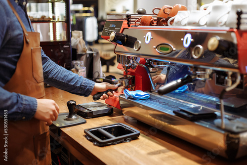 Preparation of coffee in a coffee shop by the hands of a barista using a professional coffee machine