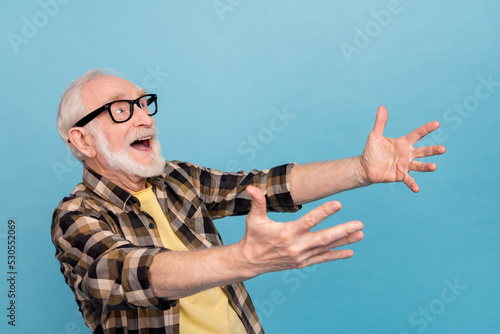 Photo of excited pretty man pensioner dressed checkered shirt eyewear looking up catching empty space isolated blue color background