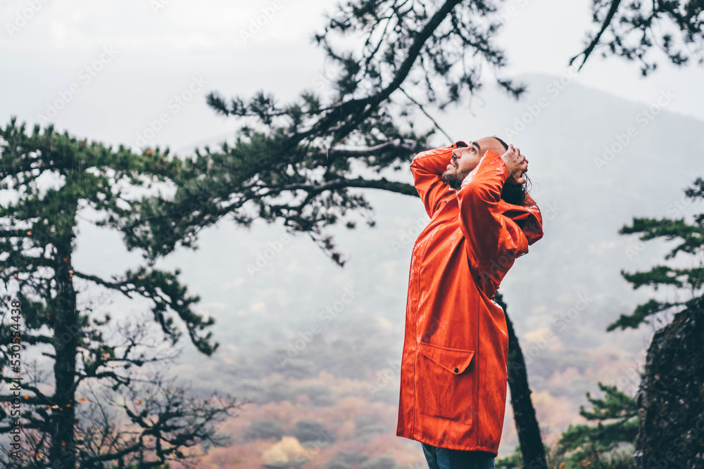 Man wearing orange raincoat in the park at rainy autumn day. Man wearing orange raincoat in the park at rainy autumn day.