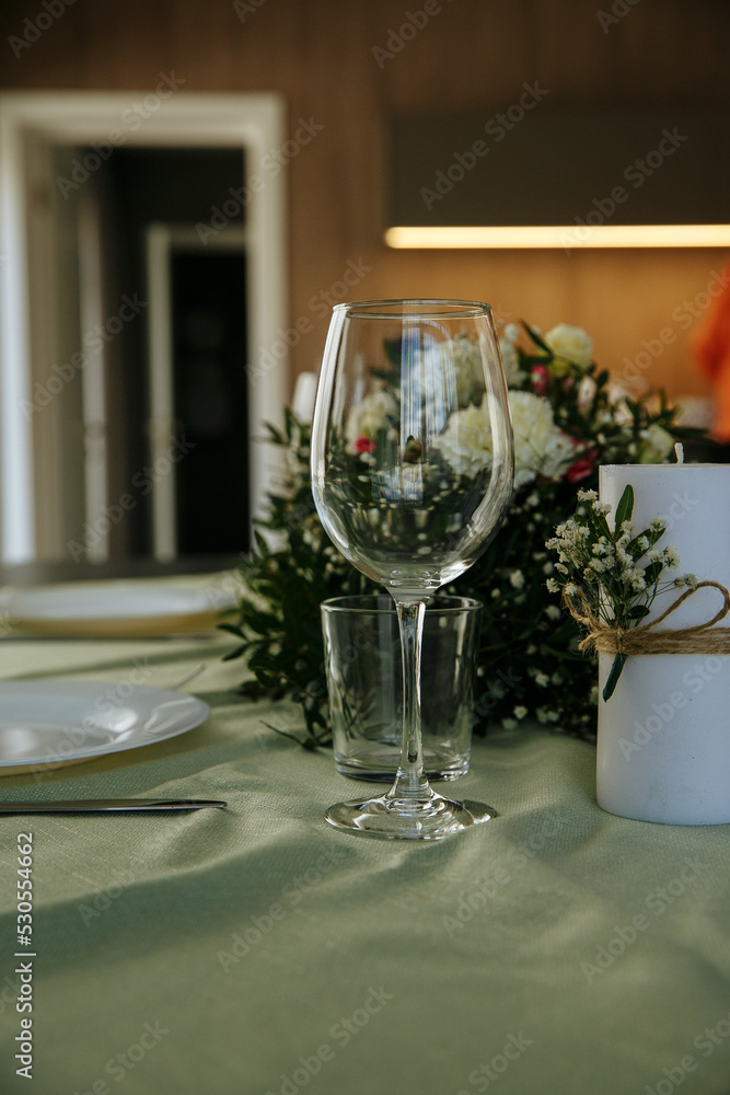 in a bright room, with daylight, a festive table is decorated, with plates and glasses in a bright room, with daylight, a festive table is decorated, with plates and glasses