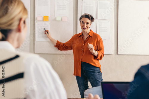 Mature businesswoman giving a presentation to her team in an office