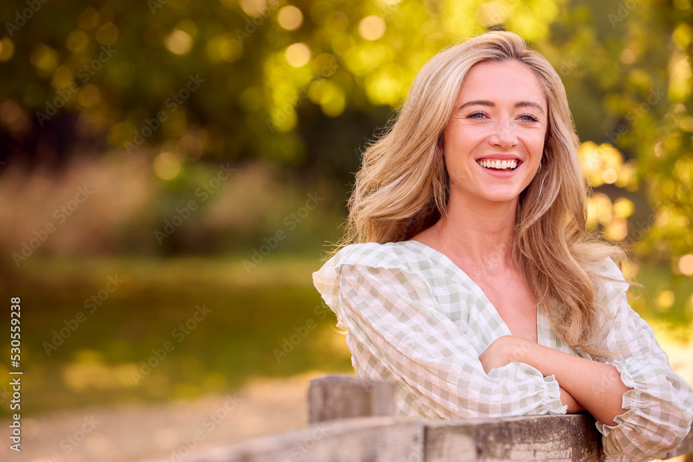 Casually Dressed Young Woman Leaning On Fence On Walk In Countryside Casually Dressed Young Woman Leaning On Fence On Walk In Countryside