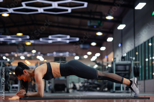 Happy beautiful young asian woman doing planking exercise fitness gym. Beautiful women in good shape from taking care of their bodies. Health concept.