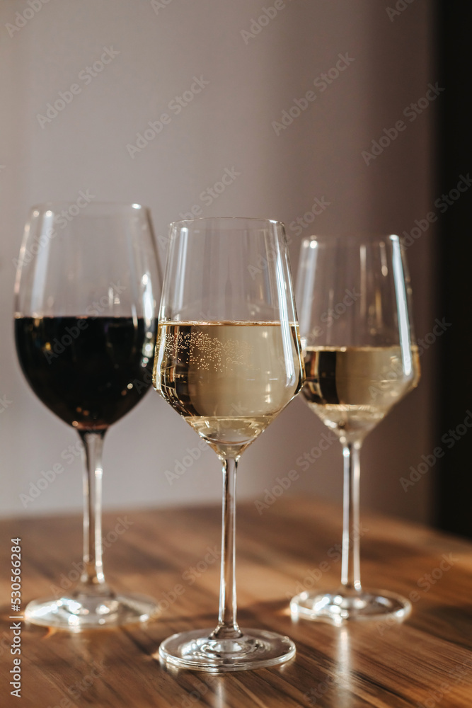 House party. Three glasses of red and white wine on the table in the living room in the rays of the setting sun House party. Three glasses of red and white wine on the table in the living room in the rays of the setting sun