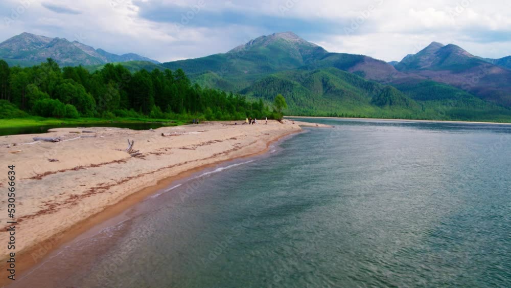 Tourists on the sunny beach of Sosnovka Bay in summer on Lake Baikal. Shooting from a drone Tourists on the sunny beach of Sosnovka Bay in summer on Lake Baikal. Shooting from a drone