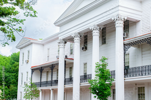 A white mansion style historical building with columns and ironwork
