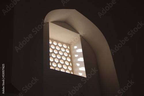 Window with hexagonial shapes underneath arc islamic architecture lightbeams enter in dark room