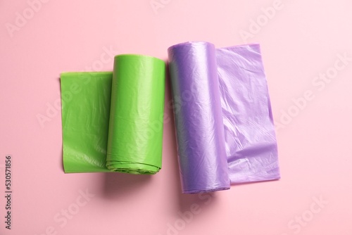 Rolls of different garbage bags on pink background, flat lay
