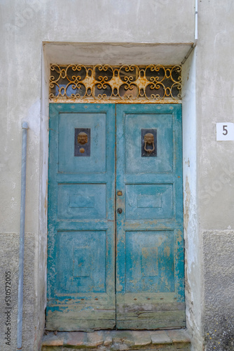 old blue wooden door with metallic knockers in town. Exterior design. Building facade.  © Kate