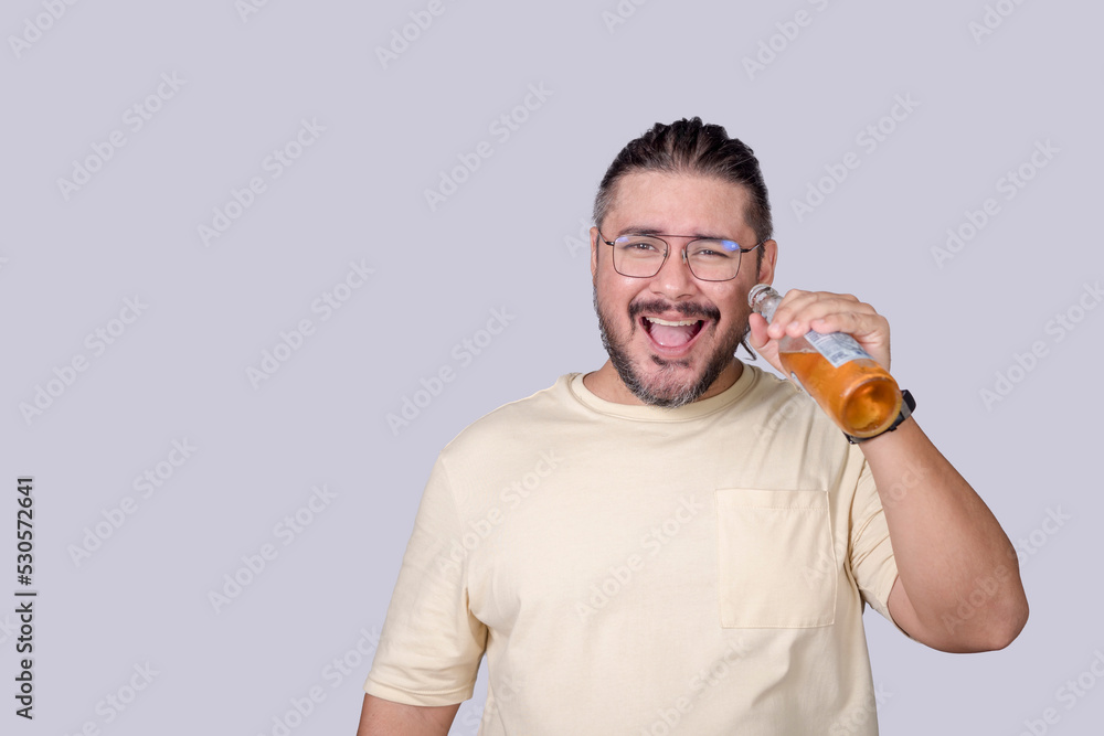 A smart guy in his 30s enjoying a bottle of light beer. Making an ahhh exclamation. Isolated in a gray background. A smart guy in his 30s enjoying a bottle of light beer. Making an ahhh exclamation. Isolated in a gray background.