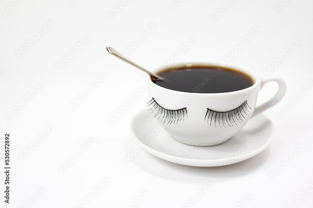 A funny white coffee cup with eyelashes on a white background. Side view. A funny white coffee cup with eyelashes on a white background. Side view.