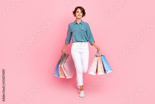 Full length photo of pretty lady trendy outfit two arm hand hold carry bag enjoy shopping isolated on pink color background