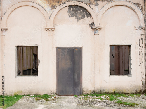 Old abandoned building with rusty iron door and broken windows. Abandoned railway station © jockermax3d