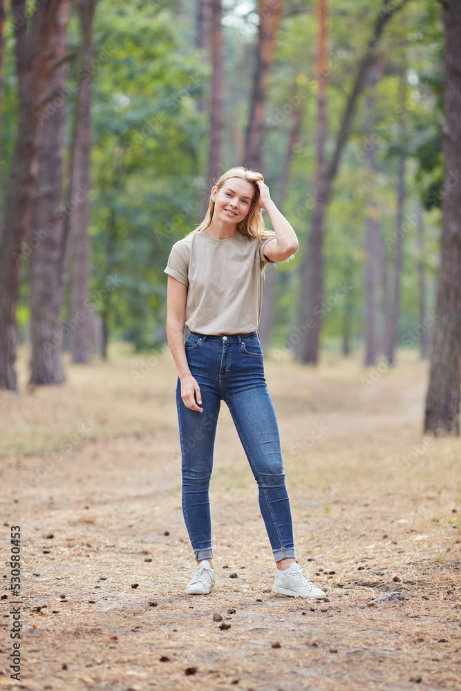 Blonde lady with natural makeup posing in a pine forest. Gorgeous blue eyed caucasian woman in beige t-shirt , enjoying summer vacation. Blonde lady with natural makeup posing in a pine forest. Gorgeous blue eyed caucasian woman in beige t-shirt , enjoying summer vacation.
