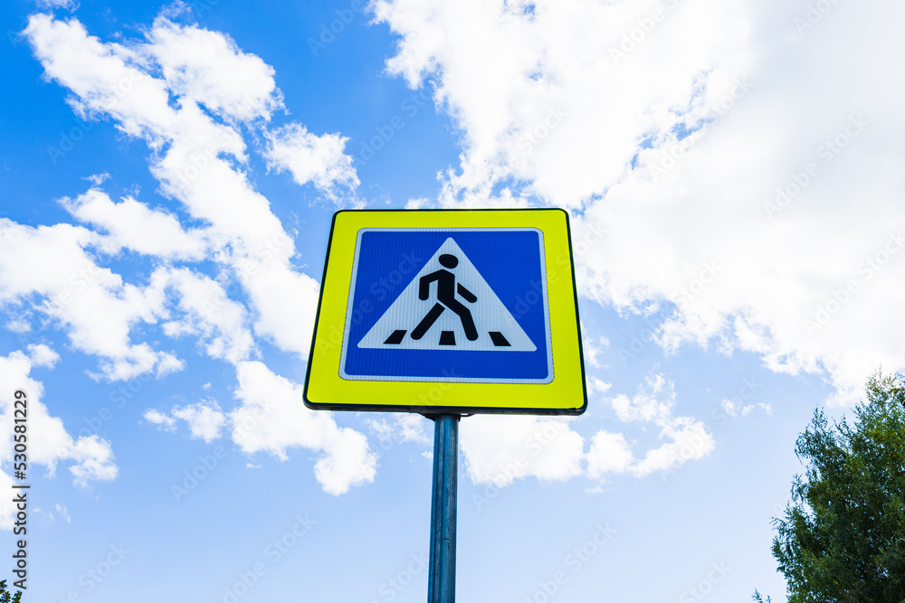 Blue and white pedestrian crossing sign on the sky background