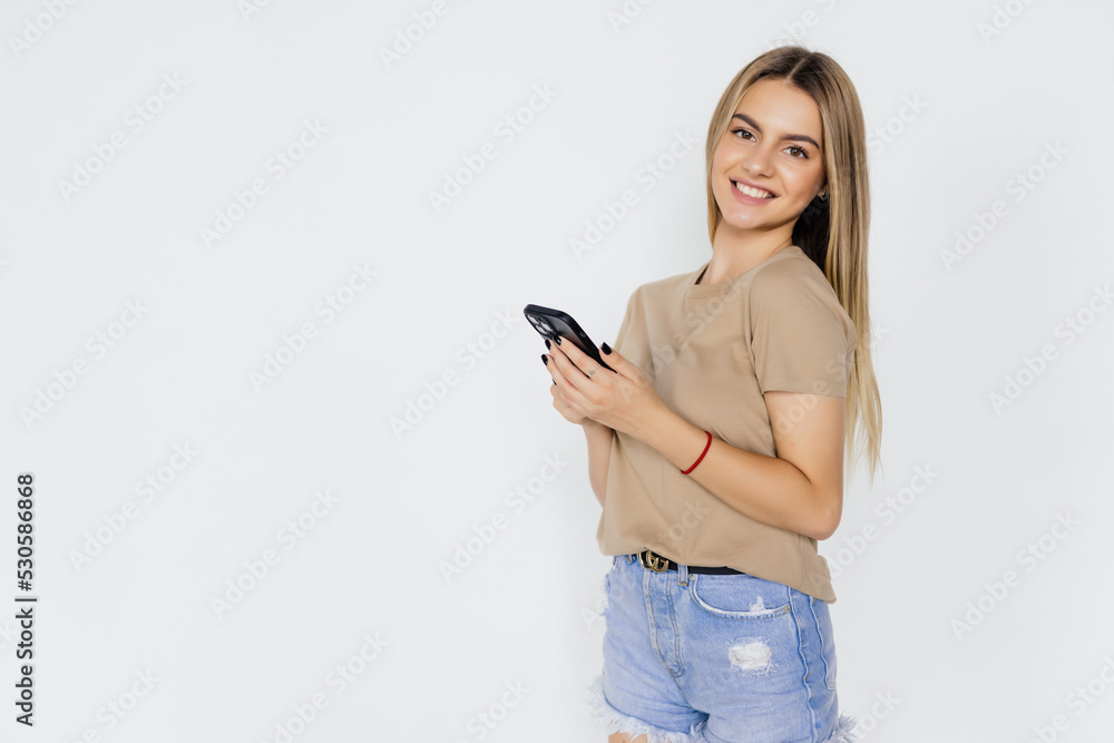 Young woman smiling while using cellphone isolated over white background Young woman smiling while using cellphone isolated over white background