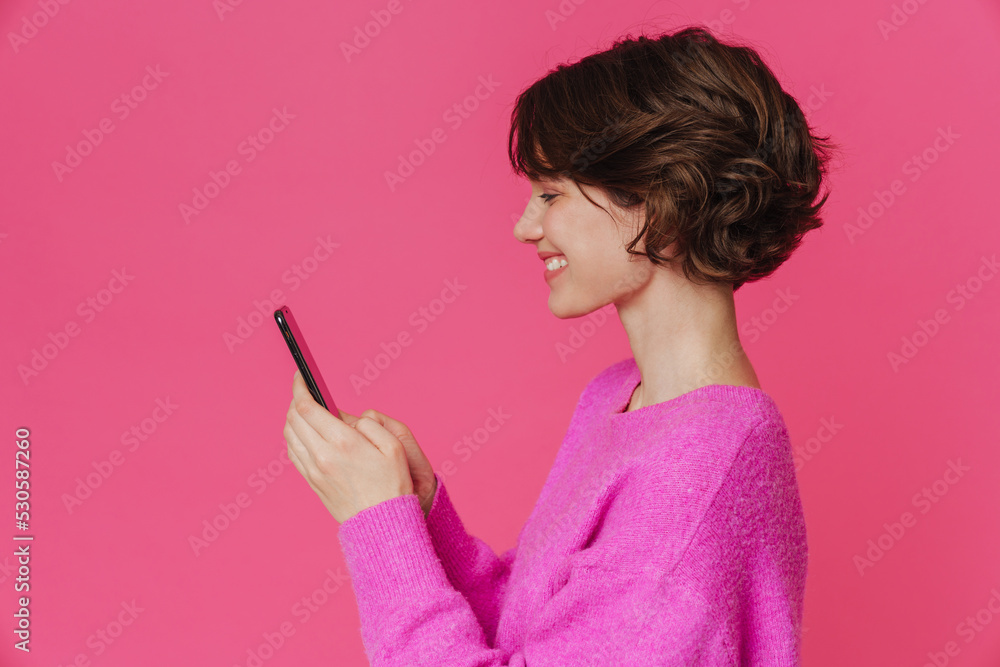 Young brunette woman smiling while using mobile phone Young brunette woman smiling while using mobile phone