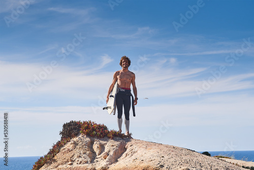 Beach surfer man posing at the hill with surf board
