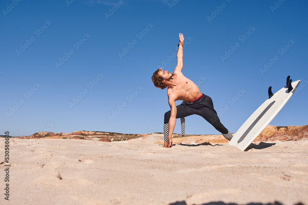 Shirtless man standing on the sand near the sea and stretching Shirtless man standing on the sand near the sea and stretching