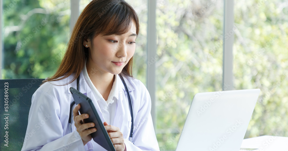 Portrait of asian senior doctor sitting in medical office while using laptop computer and checking time of appointment. Portrait of asian senior doctor sitting in medical office while using laptop computer and checking time of appointment.