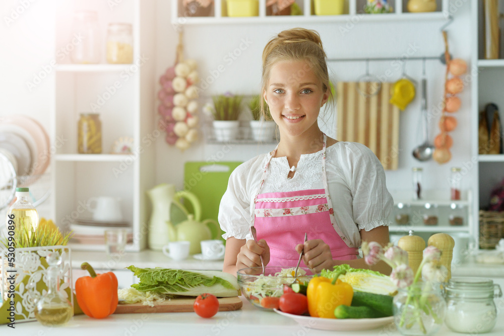Beautiful girl preparing a salad in the kitchen