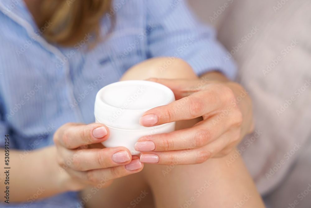 Woman's hands hold a jar of body cream. Body care at home. Close-up. Selective focus. Woman's hands hold a jar of body cream. Body care at home. Close-up. Selective focus.