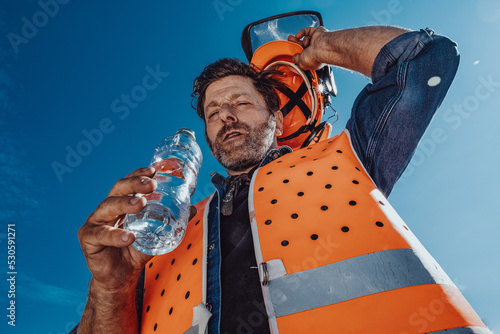 Arbeiter in Sicherheitskleidung schwitzt in der Sonne photo