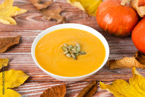 Delicious pumpkin cream soup on the wooden table. Food from seasonal vegetables. Close-up.