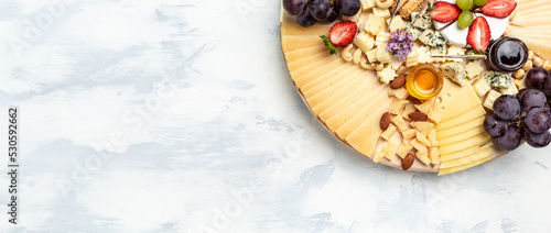Antipasto Cheese board of various types of soft and hard cheese on a light background. Long banner format. top view