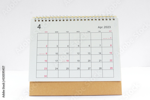 april 2023 Desktop calendar for planners and reminders on a wooden table on a white background.