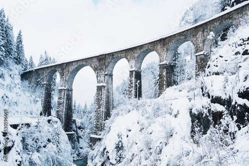 Mountain landscape with Sainte Marie bridge covered with snow in Les Houches, Chamonix valley, Eastern France. Viaduct bridge built to carry a railway over water. photo