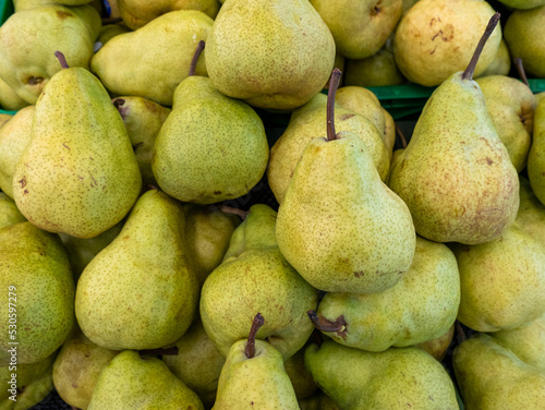 A pile of freshly picked pears stored for sale in a supermarket.