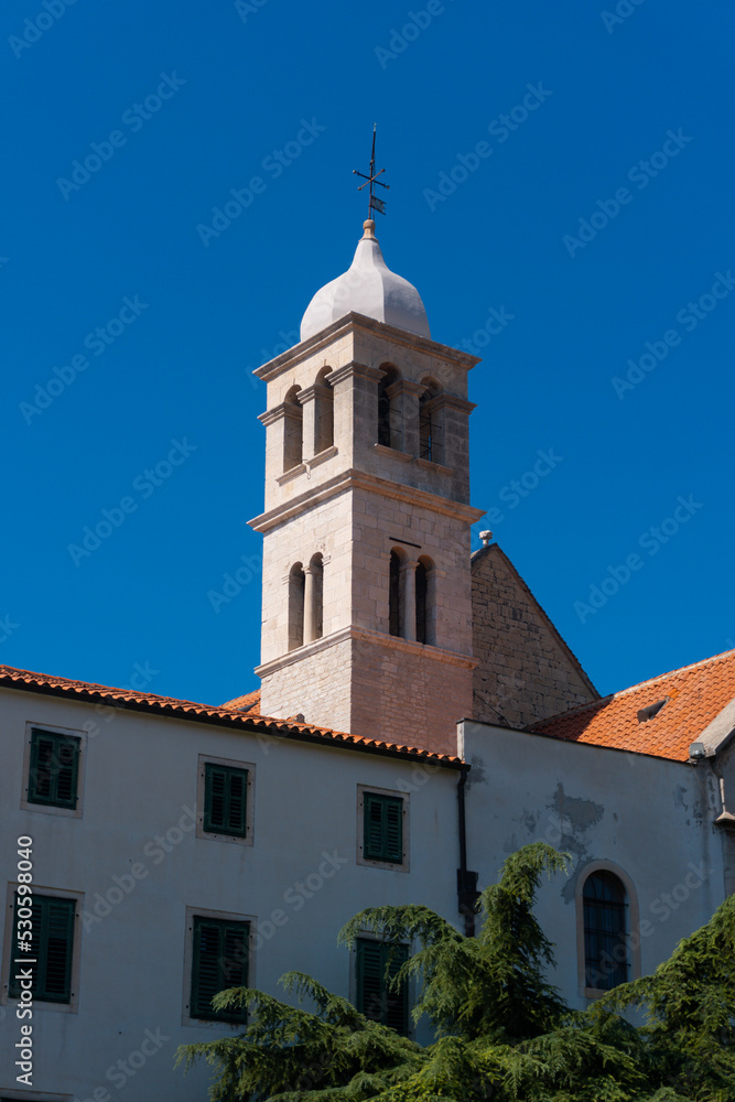 church tower (steeple) in the middle of an old town with a blue sky in Sibenik, Croatia