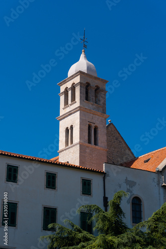 church tower (steeple) in the middle of an old town with a blue sky in Sibenik, Croatia