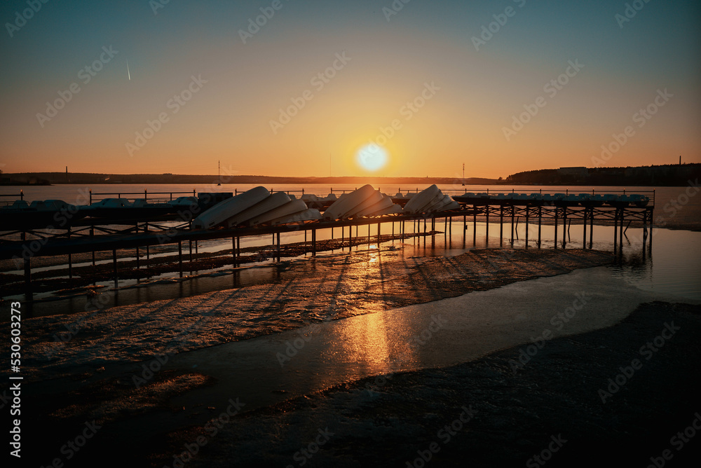 wooden pier with boats at sunset