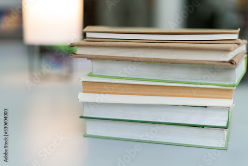 Cropped view of the many stacks of educational books for college exams in the library on a book shelves background. Studying concept