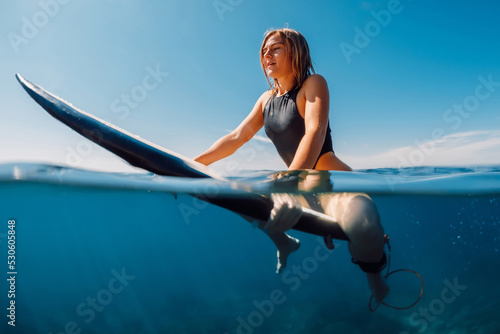 Photography Surf girl on surfboard in transparent blue ocean.