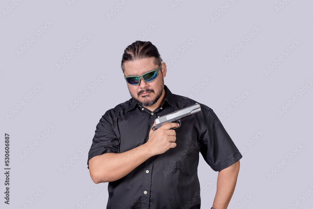 Obraz premium A ganster or henchman wearing shades showing off his handgun, in an act of intimidation.