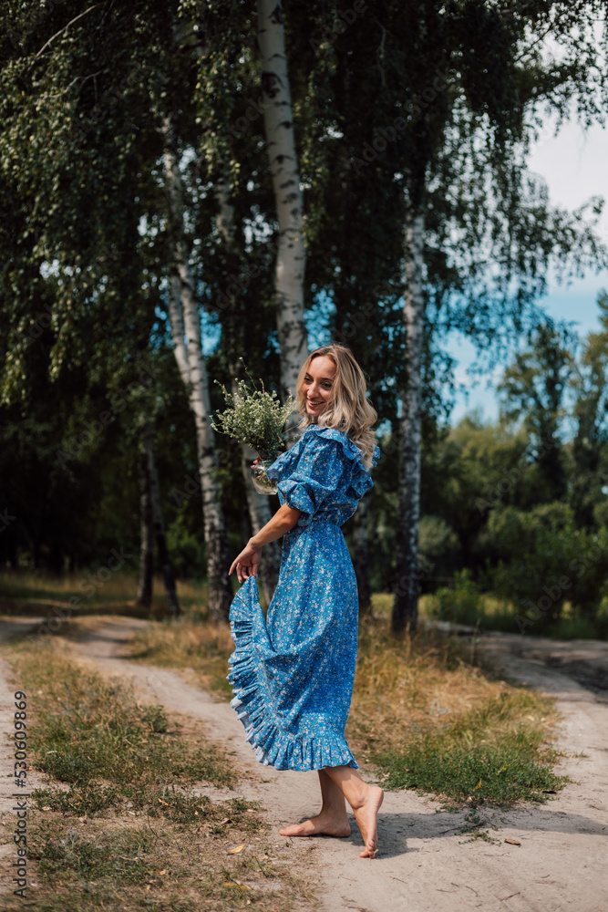 A young attractive woman with flowers in her hands walks through the forest A young attractive woman with flowers in her hands walks through the forest