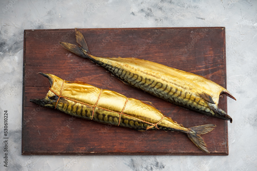 two smoked mackerel fish on a wooden board on a light background
two smoked mackerel fish on a wooden board on a light background