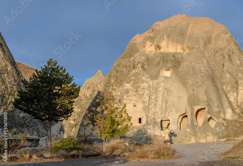 The view on partly collapsed natural rock formations and artificial caves, dovecotes inside it, known as fairy chimneys, located in Goreme, Cappadocia region, Turkey, illuminated by sun