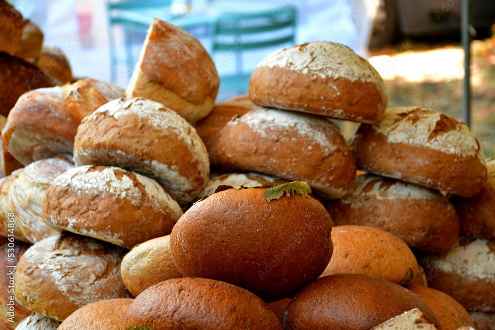 A close up on a massive pile of freshly baked bread, rolls, and buns with flour icing and some flavor enhancing additions seen during a folk fair or festival in Poland organized in summer