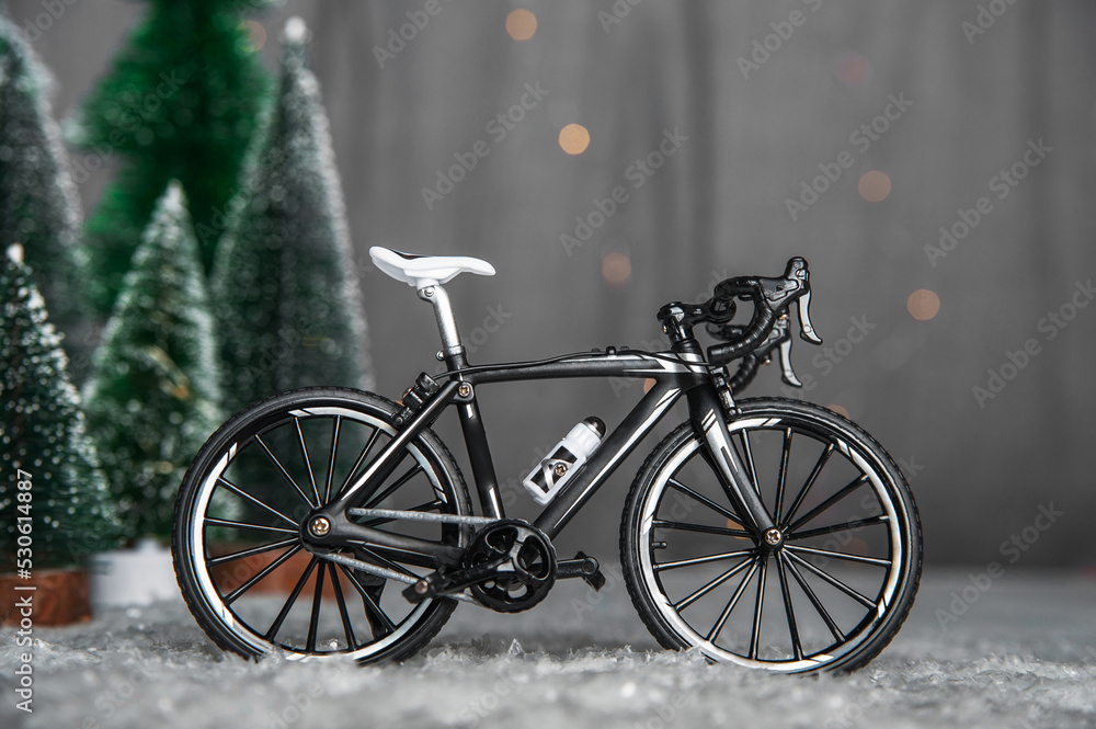 Miniature bike on background of Christmas trees and snow. Winter cycling