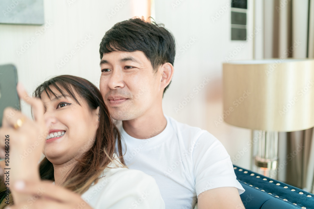 marriage couple cuddle on sofa using smartphone. happy comfortable family having conversation hugging together on couch. handsome husband touch beautiful wife indoors relax in lovely good living room marriage couple cuddle on sofa using smartphone. happy comfortable family having conversation hugging together on couch. handsome husband touch beautiful wife indoors relax in lovely good living room
