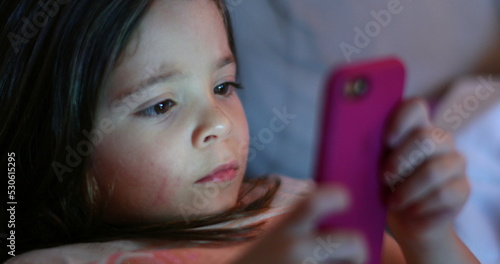 Little girl holding smartphone screen at night