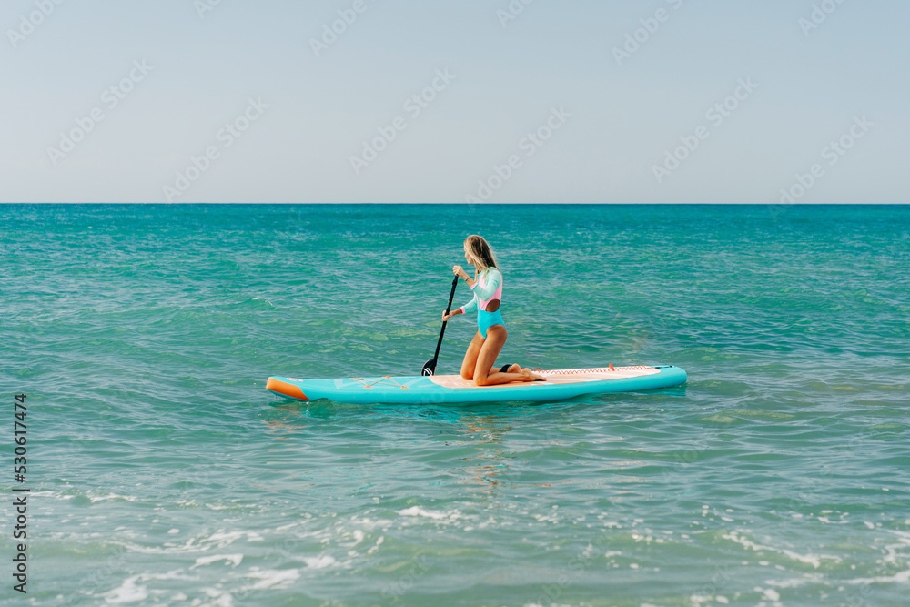 A young athletic woman is paddling on a paddleboard on the sea. A young athletic woman is paddling on a paddleboard on the sea.